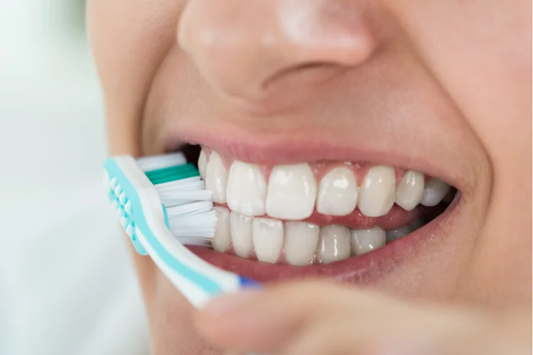 Asian man brushing his teeth to prevent bacteria buildup and maintain oral hygiene and dental veneers.