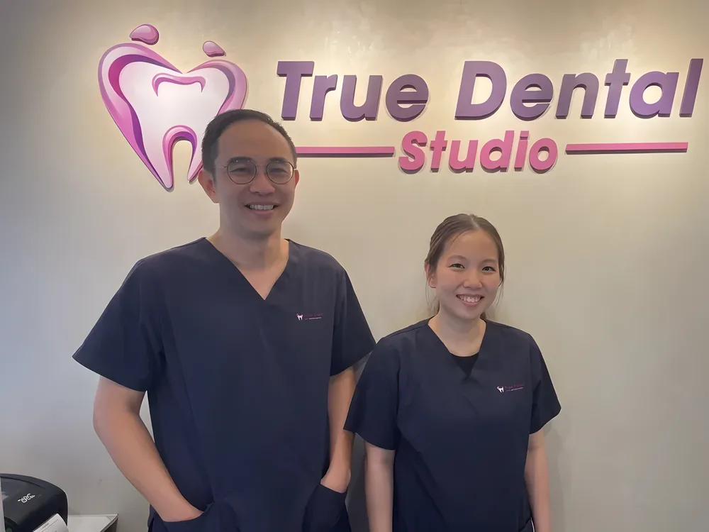 Dr Tay Chih Kien and Kalinda Teo of True Dental Studio in front of the clinic logo.