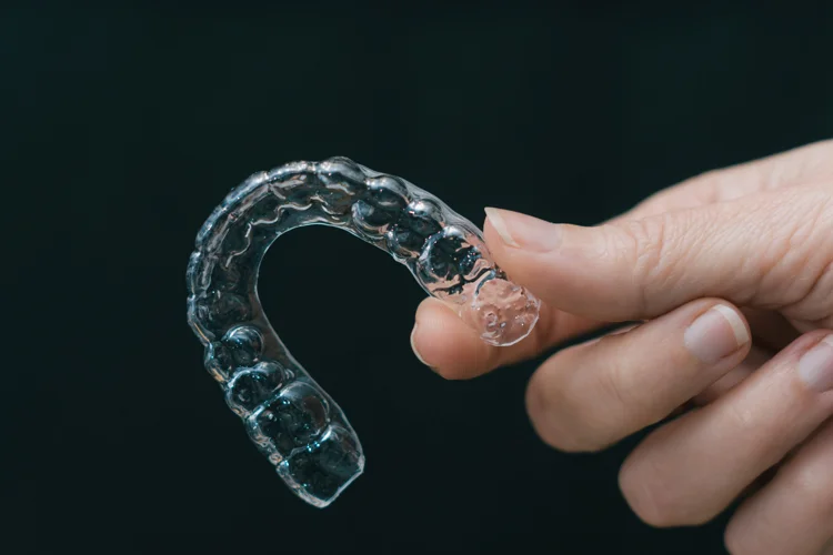 Clear dental retainers in hand.