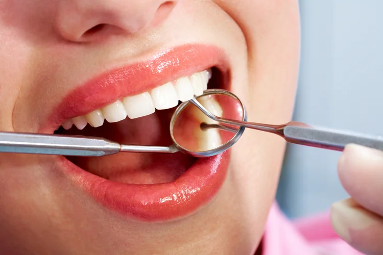 Dentist examining adult female patient’s permanent teeth during oral health consultation.