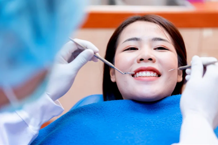 Dentist examining young asian woman teeth as part of dental-check-up.