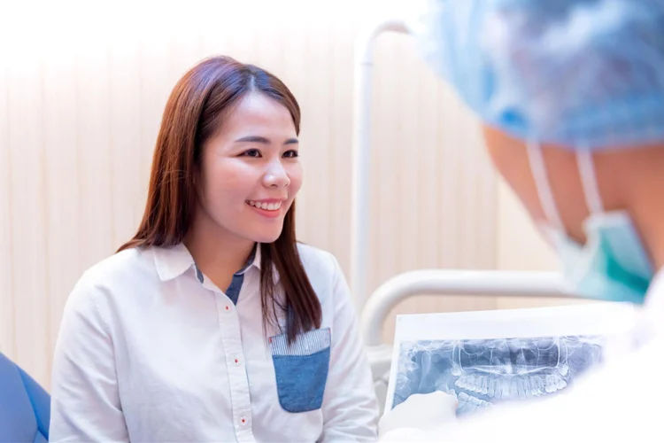 Dentist providing consultation to young asian woman after examining and cleaning her teeth.