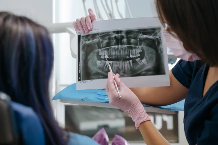 Dentist reviewing dental x ray with female patient during second opinion consultation appointment.