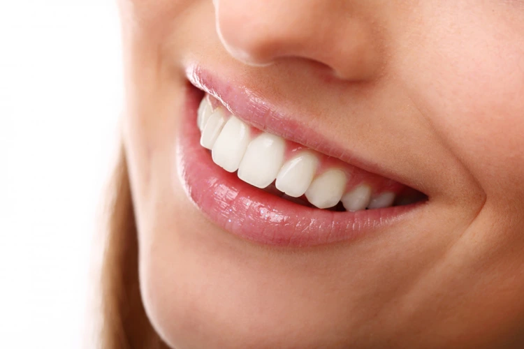 Woman confidently showing off her bright and beautiful smile after undergoing professional teeth whitening conducted by a dentist.